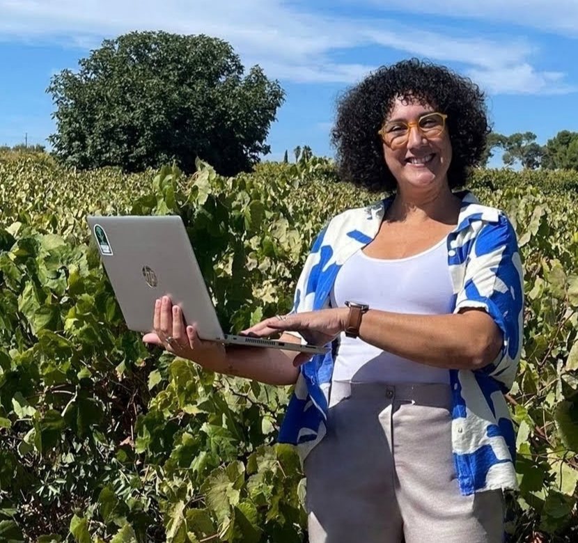 Carolina, fundadora d'Optimiza, amb el portàtil enmig d'una vinya